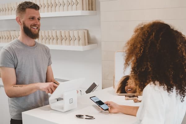 Dono de loja passando o cartão de uma cliente no balcão
