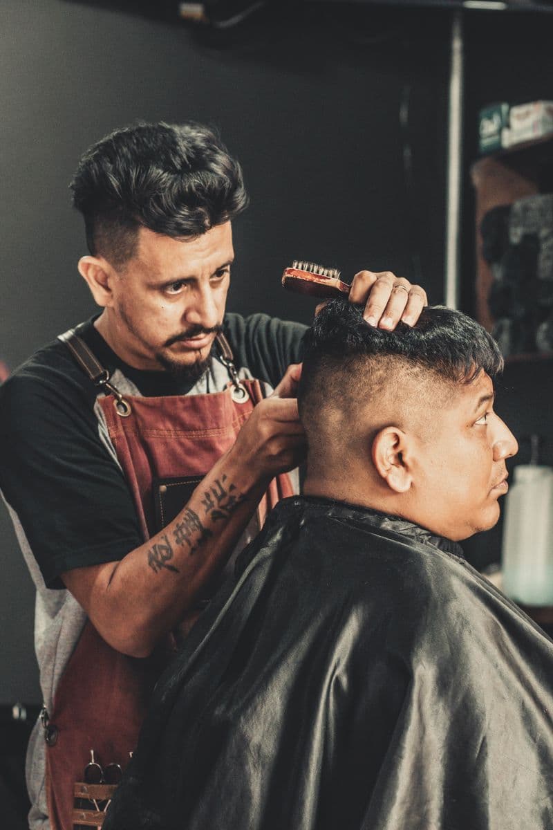 Barbeiro finalizando o corte de um cliente na cadeira